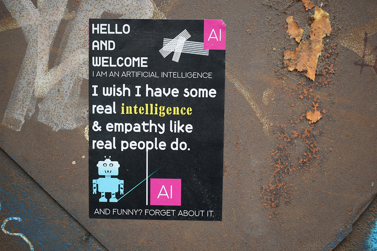 Street art poster with humorous AI statement on a rusty metal wall, featuring a cartoon robot and bold typography about intelligence and empathy.