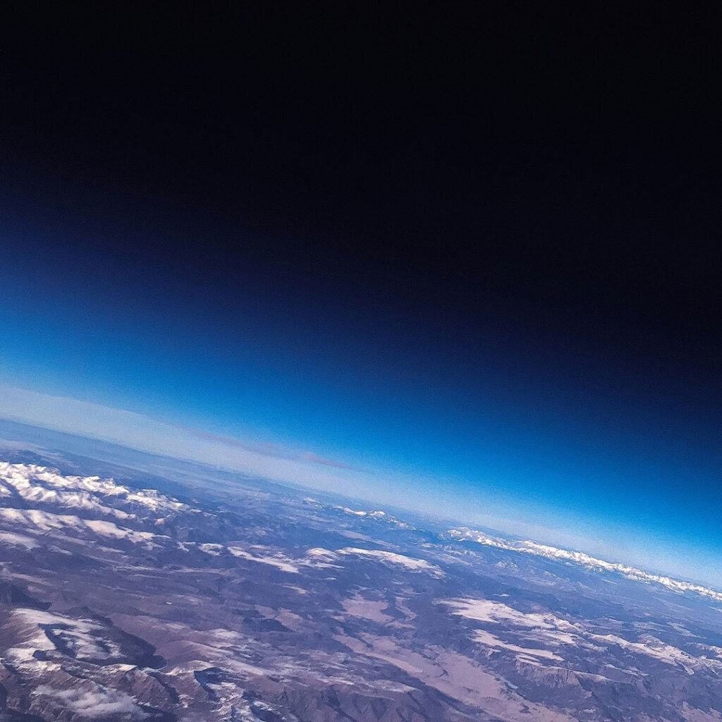 View from the stratosphere showing the curvature of Mother Earth with mountains and atmosphere fading into space.